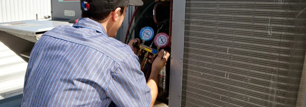 HVAC technician servicing a condenser unit in Mount Carmel